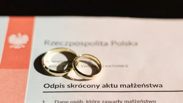 Dwa złote obrączki na odpisie skróconym aktu małżeństwa. Dokument potwierdza, ile jest ważny akt małżeństwa.