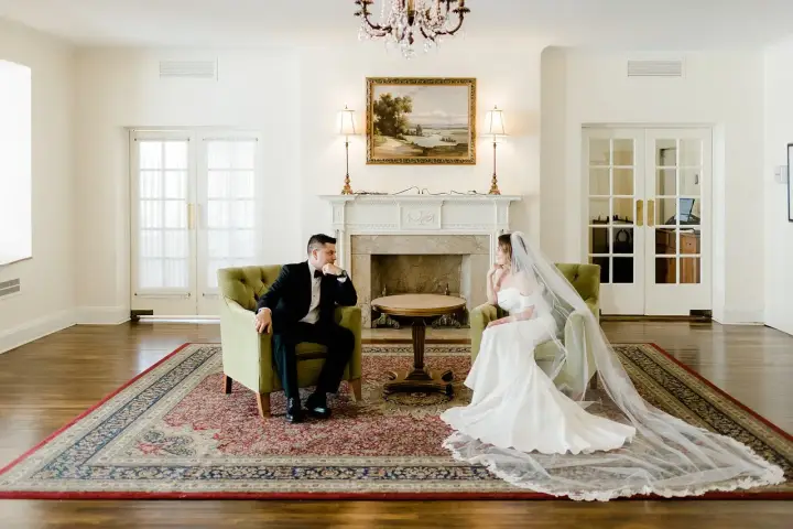 Para młoda siedzi naprzeciwko siebie w eleganckich fotelach, przeżywając ostatnie chwile przed ślubem.